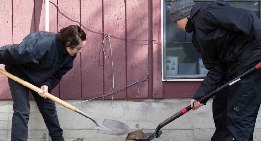 two students use shovels while doing a service project with outward bound